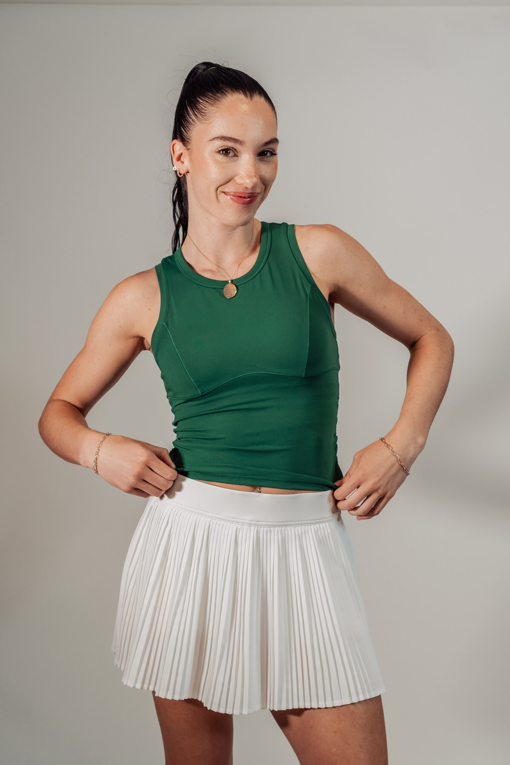 Front view of model Nikki wearing white pleated skort and green Good Dink green sleeveless top